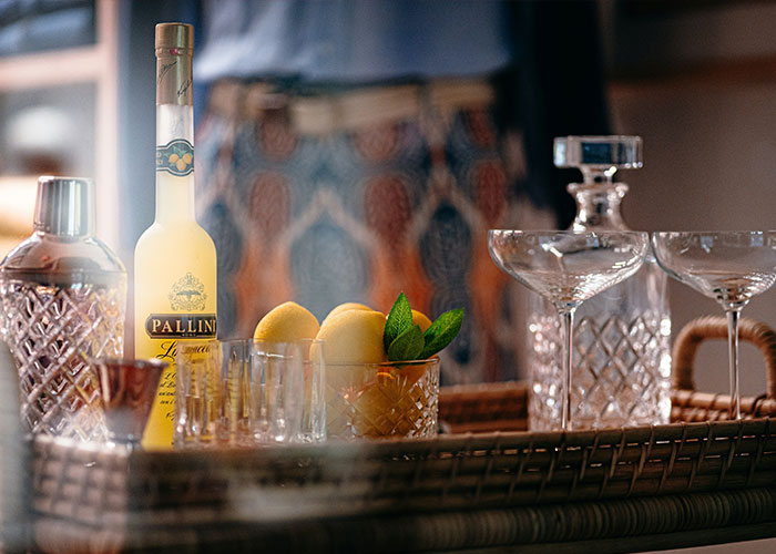 Bottle of limoncello with lemons and glassware on a tray, highlighting poisoned limoncello in tragic incident.
