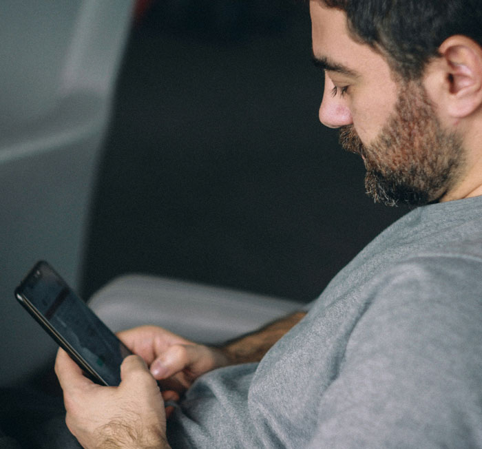 Hombre con barba usando teléfono móvil, ilustrando cómo los teléfonos ayudan a descubrir verdades ocultas.