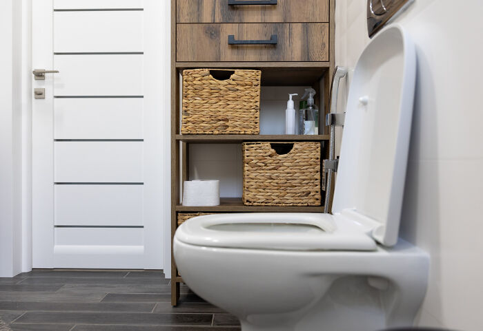 Modern bathroom with white toilet and wooden storage baskets, illustrating absurd dealbreakers in relationships according to women.