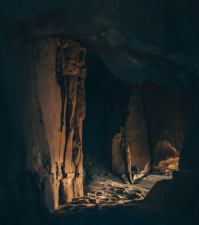 Dark cave passage illuminated by soft light, evoking a mysterious and eerie atmosphere related to cops witnessing horrible scenes.