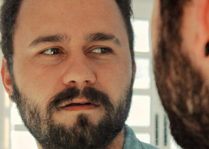 Man with beard looking at his reflection in a mirror illustrating incredible coincidences that seem fake but are true.