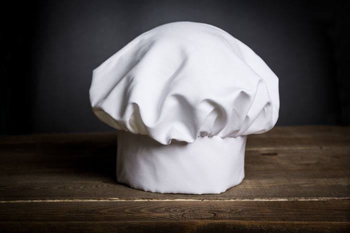 White chef hat resting on a wooden surface, illustrating an unrelated image to security guards sharing creepy experiences.