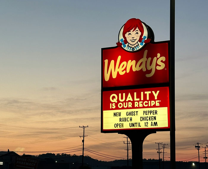 Wendy's restaurant sign at sunset featuring new ghost pepper ranch chicken, illustrating brilliant loopholes exploited.