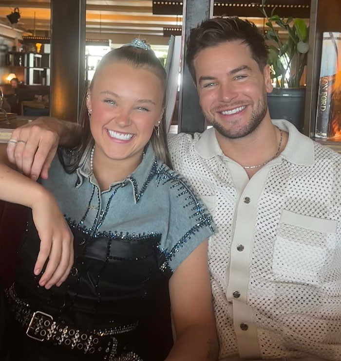 JoJo Siwa smiling with a man in casual outfits, sharing joyful moment after confessing her marriage plans.