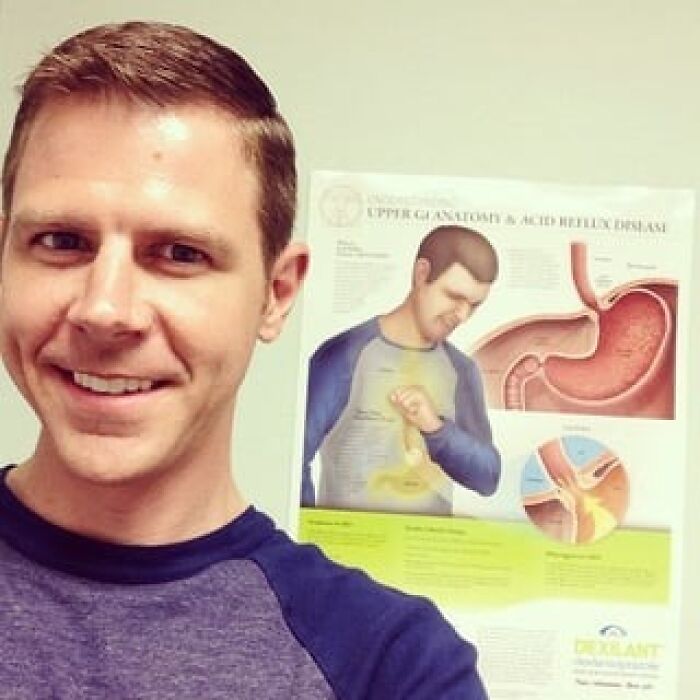 Man smiling in front of a medical poster, representing wholesome posts to distract from world horrors.