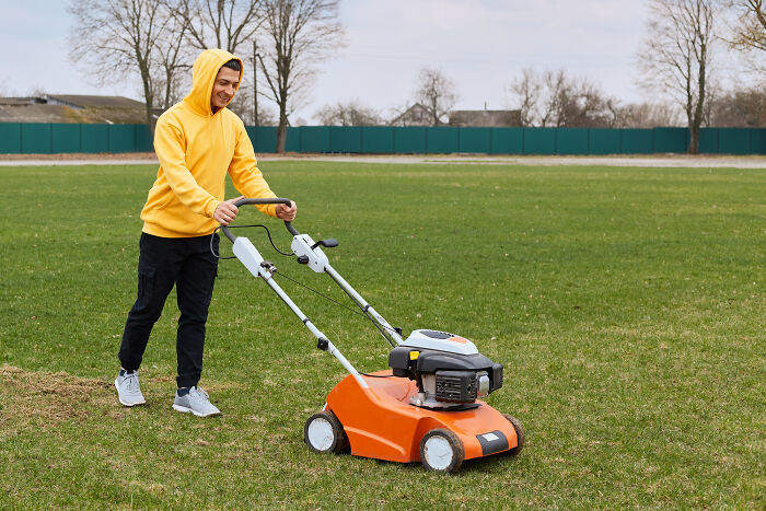 Man in yellow hoodie mowing lawn outdoors showing absurd dealbreakers in relationships leaving men clueless.