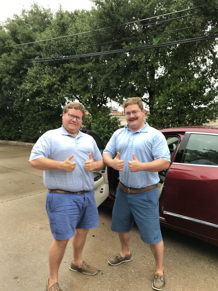 Two men in matching blue outfits giving thumbs up beside a car, a wholesome moment to distract from world worries.