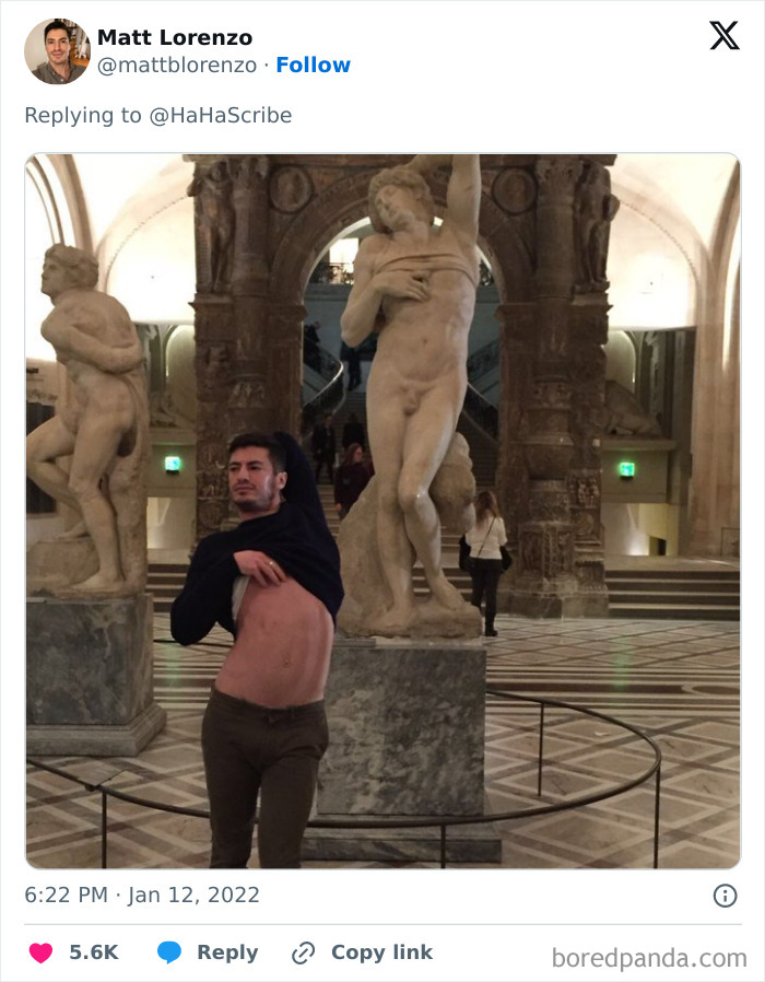 Man in museum creatively imitating iconic art statue pose by lifting his shirt in front of classical sculptures.