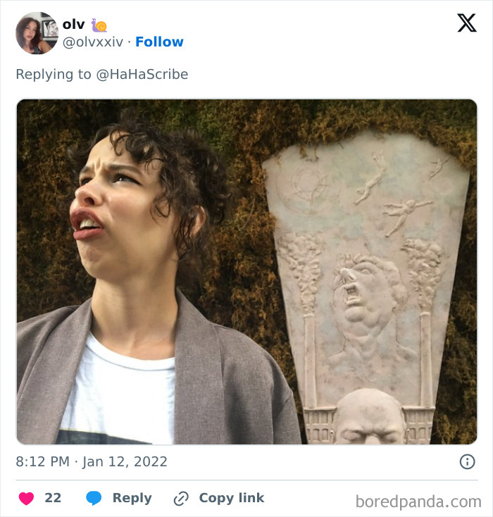 Person making a funny face standing next to a carved stone artwork, showcasing life imitating art in a creative way.