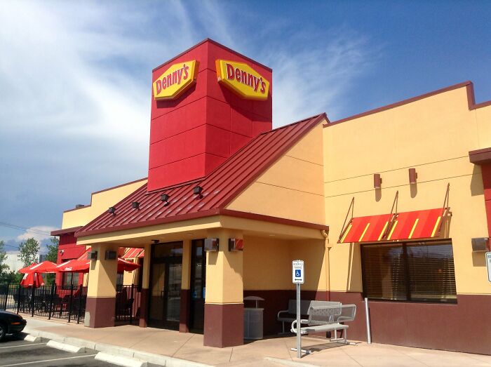 Denny's restaurant exterior with red and yellow signage under a clear sky, related to health violations in restaurants.