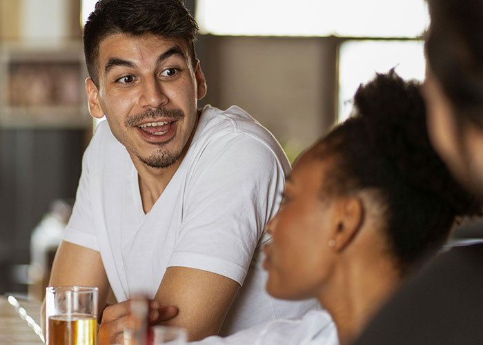 Group of friends sharing stories and laughing over drinks, illustrating incredible coincidences conversations.