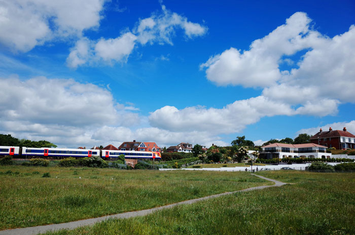 Train passing through countryside near homes under a vibrant sky, illustrating brilliant loopholes people exploited for savings.
