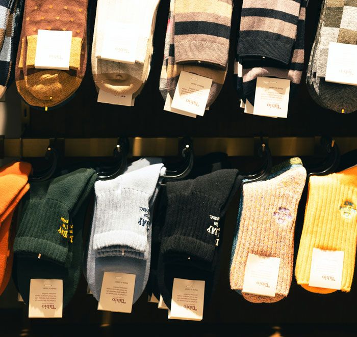 Various colorful socks neatly arranged on hangers in a retail display focusing on comfort and sleep benefits.