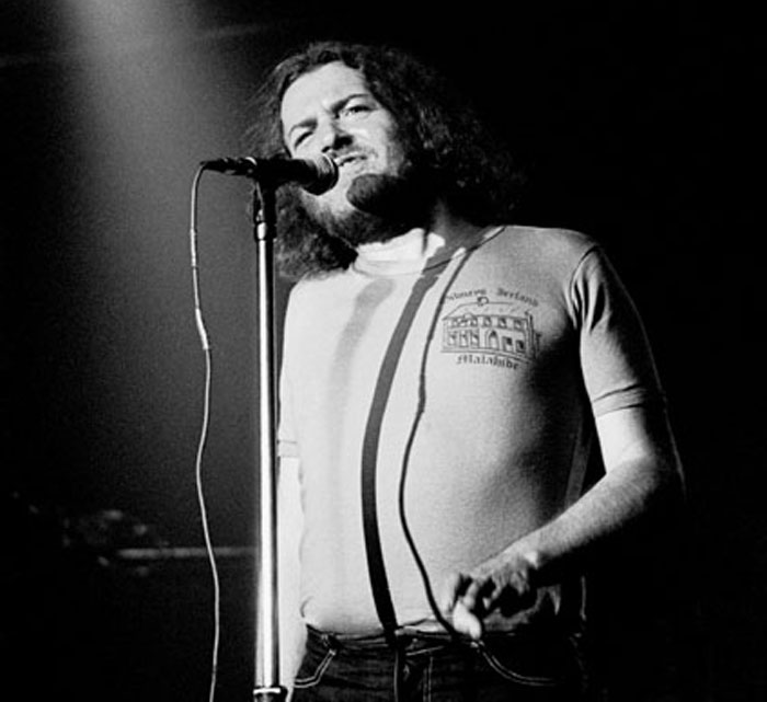 Black and white photo of a male singer performing live on stage during a concert fans wish they had skipped.
