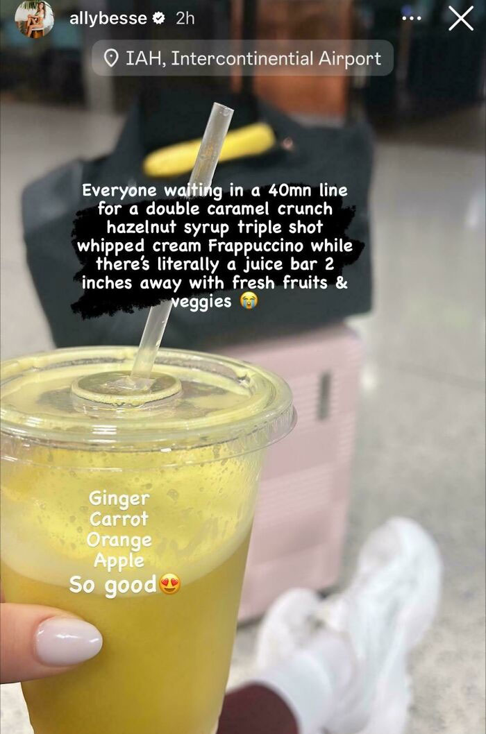 Person holding a fresh juice with ginger carrot orange apple near gym gear and shoes, promoting fitness lifestyle.