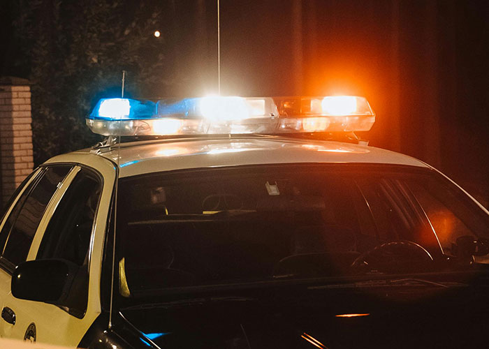 Police car with flashing lights at night, related to a collection of amusing criminal fails captured on camera.