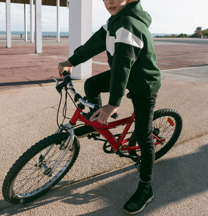 Child learning to ride a red bicycle outdoors, illustrating creativity like exploiting brilliant loopholes with zero regrets.