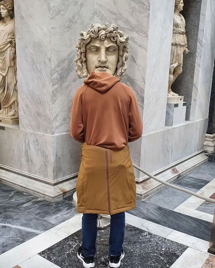 Person standing in front of a statue, creating a funny coincidence with the statue head perfectly aligned as their own.