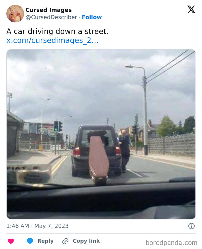 A disturbing picture showing a car driving down a street with a coffin awkwardly attached to the back.