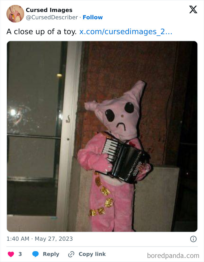 Cursed toy in a pink suit with large black eyes playing an accordion, fitting disturbing pictures SEO keyword.