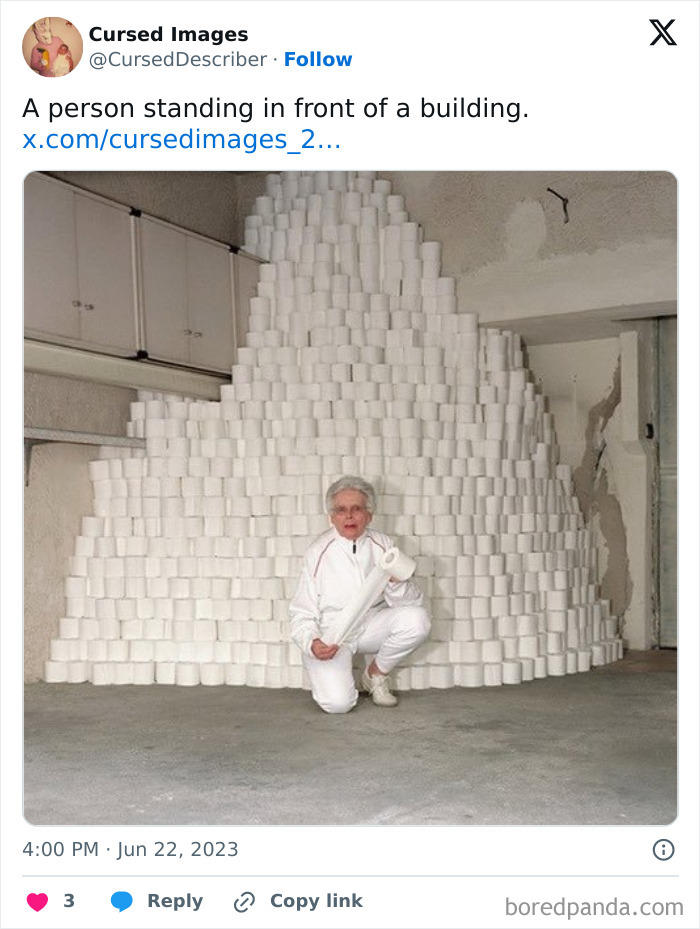 Elderly person in white clothing posing with a large, pyramid-shaped stack of toilet paper rolls indoors.