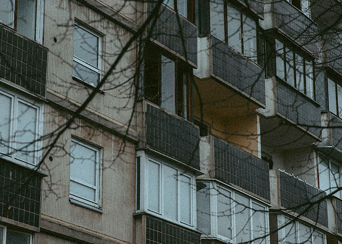 Dark, eerie apartment building exterior with shadowy branches, evoking a sense of terrifying true stories and mystery.