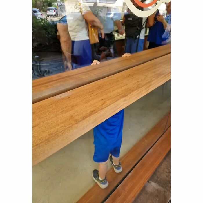 Child appears to be floating in air due to reflection in a street photo full of funny coincidences.