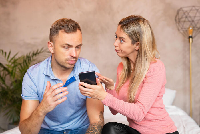 Couple discovering secret stories on phone while online surfing, showing surprise and concern in a home setting.