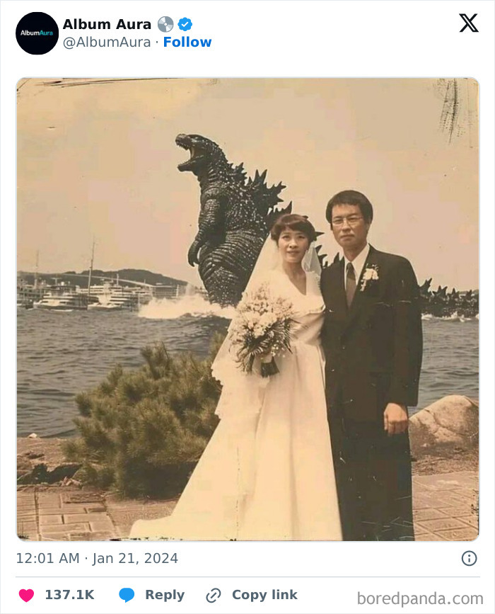 Bride and groom posing for a wedding photo by the water with a giant Godzilla figure in the background, weird and cursed.
