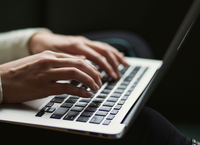 Hands typing on a laptop keyboard in low light, illustrating brilliant loopholes people exploited for savings.