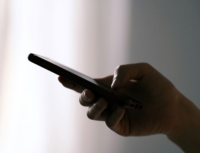 Mano sosteniendo un teléfono móvil en primer plano, destacando el uso de teléfonos para revelar verdades ocultas.