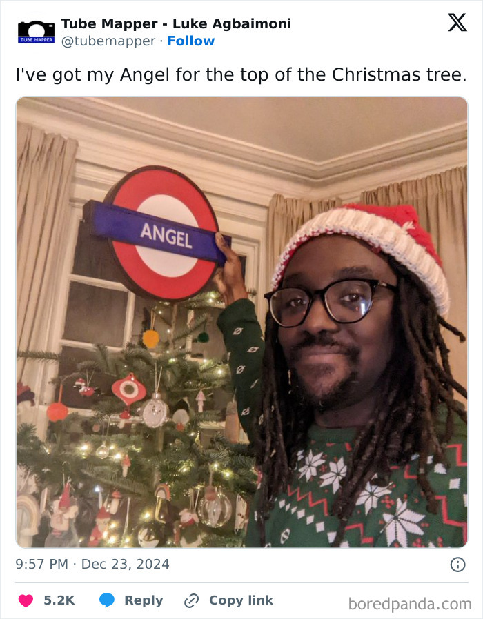Man wearing a Santa hat and Christmas sweater holding an Angel tube station sign for Great London memes humor.