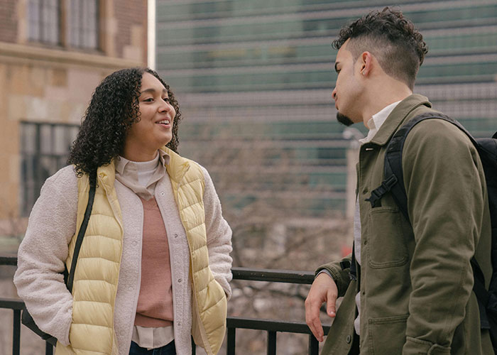 Two people casually talking outdoors in an urban setting, illustrating incredible coincidences that sound fake but are true.