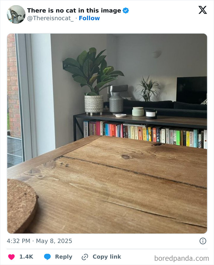 Cat camouflaged on wooden table blending seamlessly into the background in a modern living room setting.