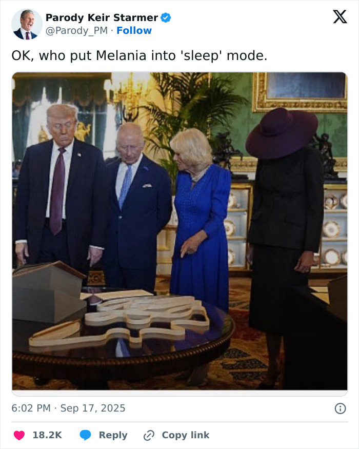 Melania Trump in a dark outfit and large hat standing with UK royals, outfit in the UK brutally mocked in a formal room. Melania Trump in a dark outfit and large hat standing with UK royals, outfit in the UK brutally mocked in a formal room.