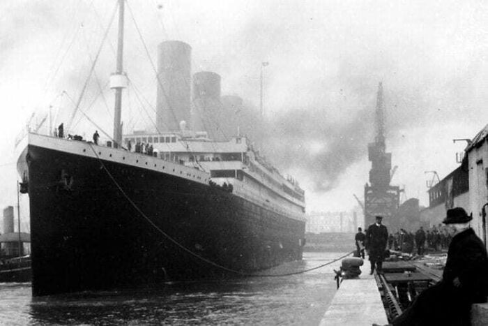Rare historical photo of the Titanic docked at port with crew and dockworkers preparing for departure.