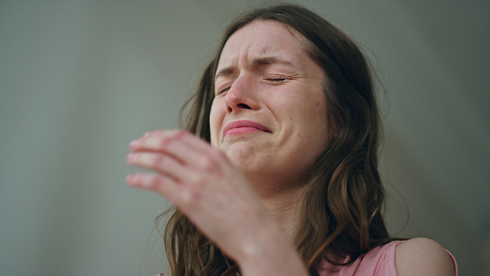 Woman refusing to give up her plane seat, showing emotional distress and almost crying in a close-up portrait.