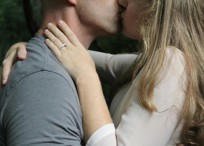 Couple sharing a close, intimate kiss with a focus on the woman&rsquo;s hand and ring, depicting friends dating the same guy.