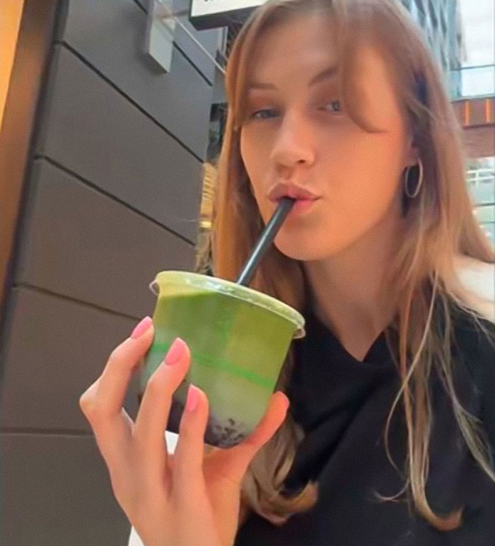 Young woman drinking matcha from a plastic cup with a straw as a public warning about matcha health risks.