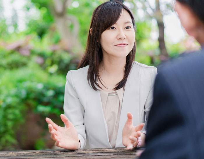 Woman in light blazer talking outdoors, appearing thoughtful about her model boyfriend being out of her league.