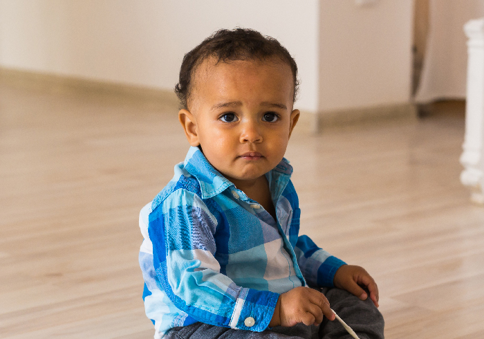 Toddler sitting alone on the floor looking sad, representing single mom abandoning toddler parents restarting life concept.