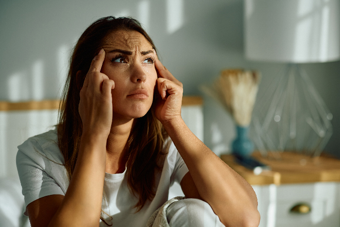 Worried young woman sitting indoors, reflecting on bride risks and friendship issues involving baby at a wedding event. Worried young woman sitting indoors, reflecting on bride risks and friendship issues involving baby at a wedding event.