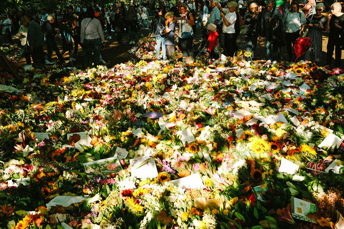 Crowd gathered around numerous floral tributes in London, capturing the atmosphere after the Queen’s passing.