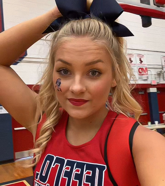 Cheerleader wearing a red uniform with bow in gym, related to newborn found stuffed in her closet and university dropout.