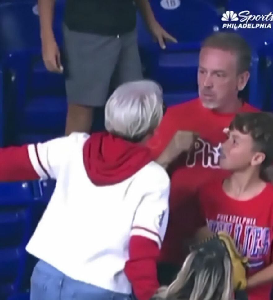 Woman wearing Phillies gear in a confrontation during a home run ball meltdown at a Philadelphia Phillies game.