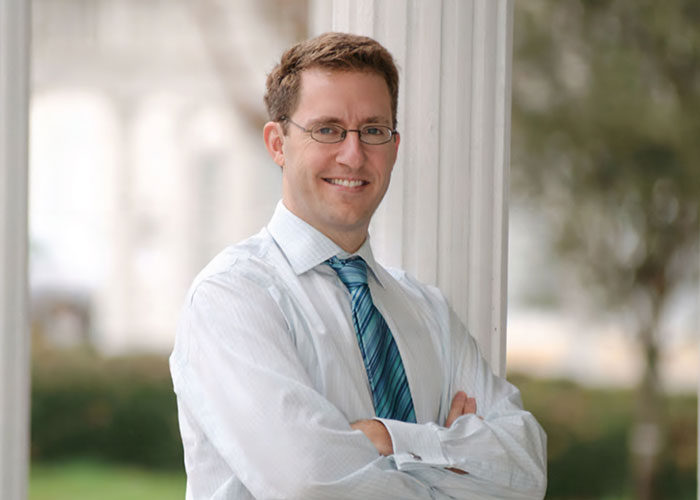 Smiling juror standing with arms crossed outdoors, sharing insights after grandma's court meltdown over viral plot case.
