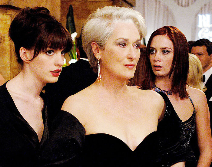 Scene from The Devil Wears Prada featuring three women in elegant black dresses at a formal event.