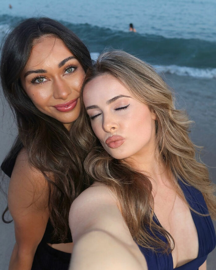 Two tourists taking a selfie on the beach, representing confused tourists boarding a flight to Africa instead of France.