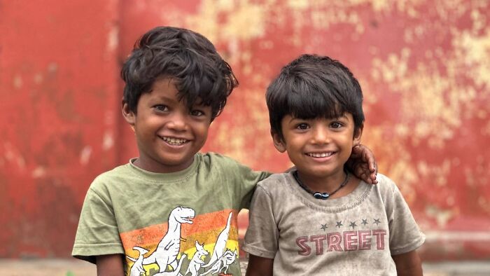 Two smiling boys embracing each other, captured in street photography showing humanity in its purest form.