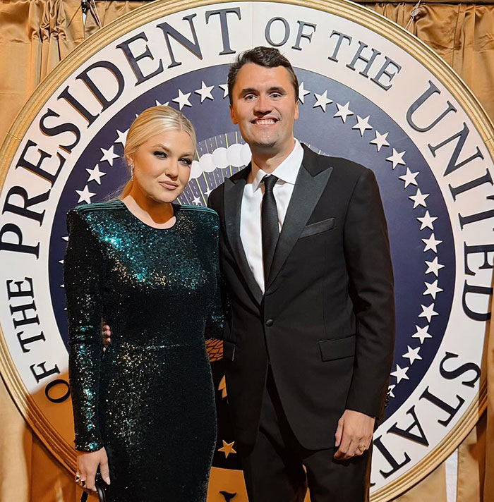 Charlie Kirk and his wife posing in formal attire in front of the presidential seal at a high-profile event.